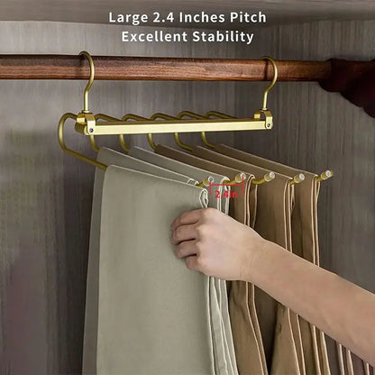 Gold pants hanger with 2.4 inches pitch holding multiple neatly folded pants in wooden closet