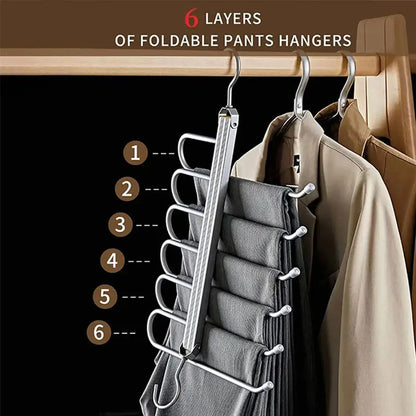 6-layer foldable pants hanger with six pairs of pants hanging next to beige jackets on wooden rack